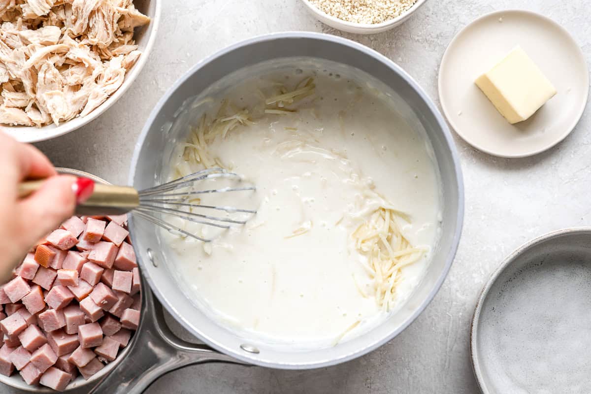 stirring cheese into cream sauce in a saucepan.