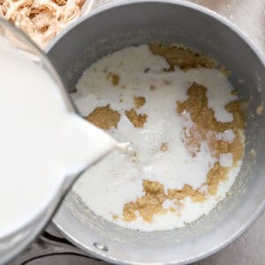 pouring milk over a roux in a saucepan.