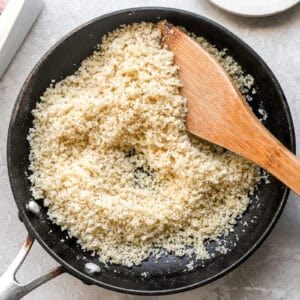 toasting breadcrumbs in a skillet with a wooden spoon.