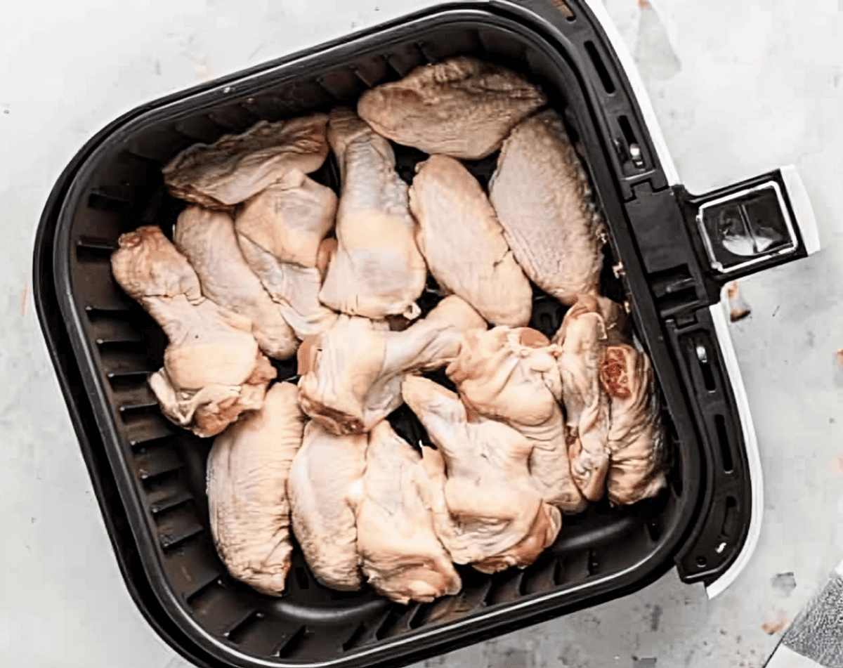 Raw chicken wings in the basket of an Air Fryer.