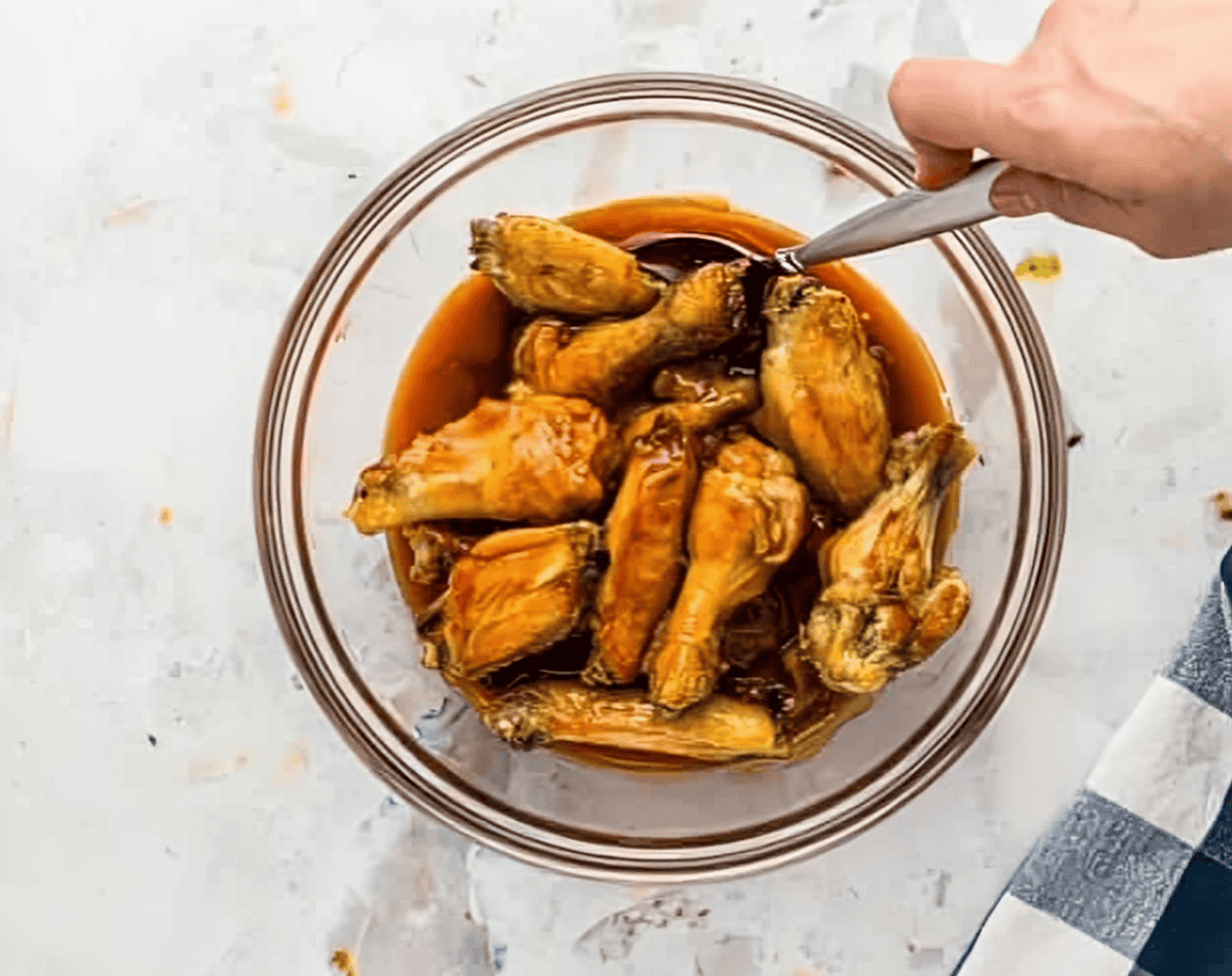 Chicken wings in a bowl of buffalo sauce.