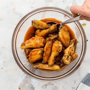 Chicken wings in a bowl of buffalo sauce.