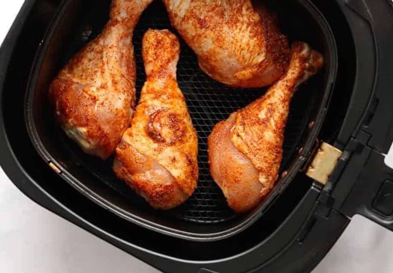 Fried chicken legs in the basket of an Air Fryer.