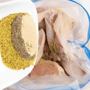 Adding lemon pepper seasonings to a bag with chicken wings.