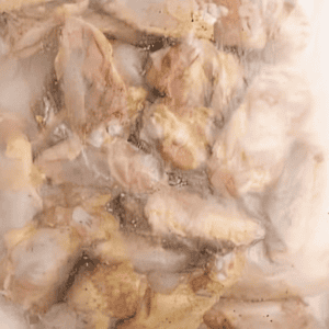 Chicken wings marinating in a bag.