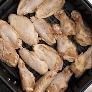 Lemon pepper marinated chicken wings cooking in the basket of an Air Fryer.