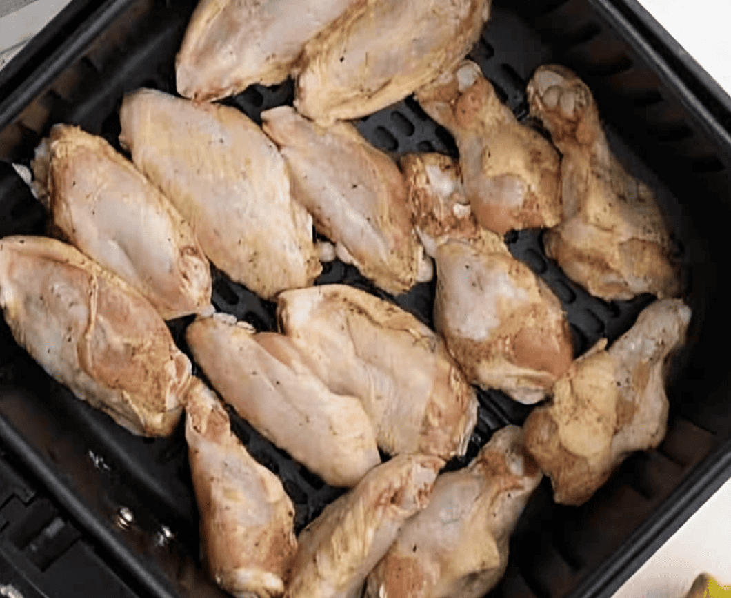 Lemon pepper marinated chicken wings cooking in the basket of an Air Fryer.