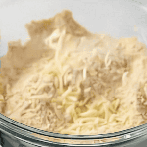 Breading mixture and shredded cheese in a glass mixing bowl.