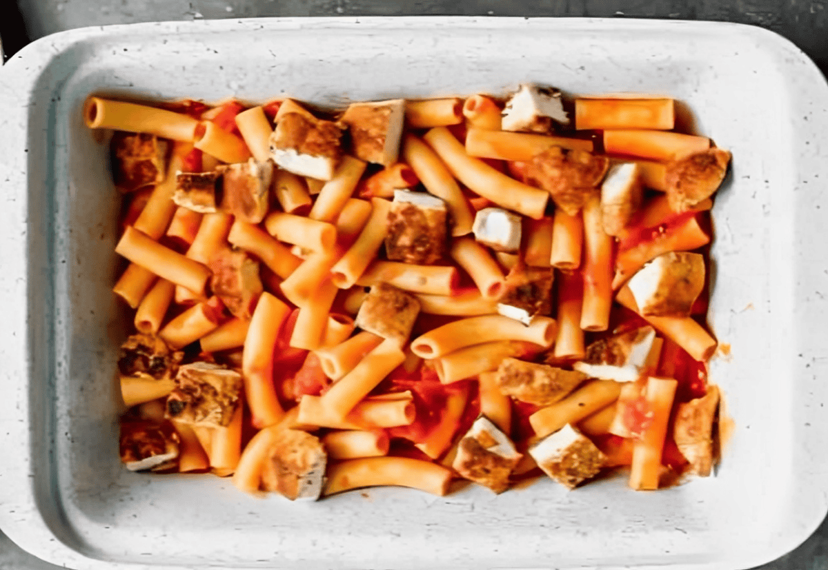 Ziti and cubes of chicken in a casserole dish.