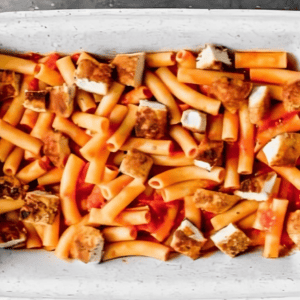 Ziti and cubes of chicken in a casserole dish.