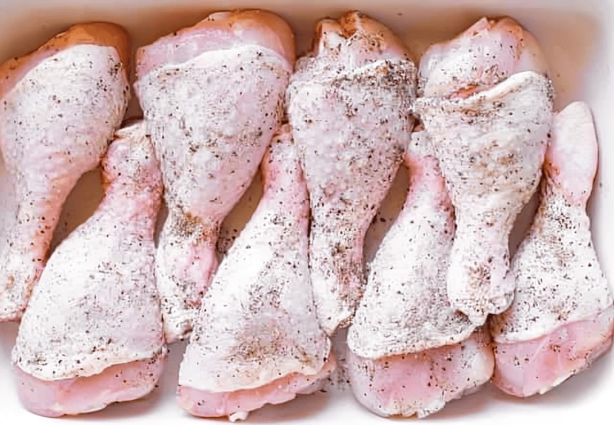 Raw chicken drumsticks coated with spices.