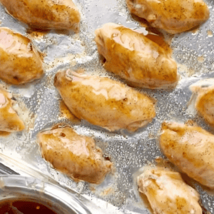 Chicken wings coated with sweet chili sauce, on a baking tray.