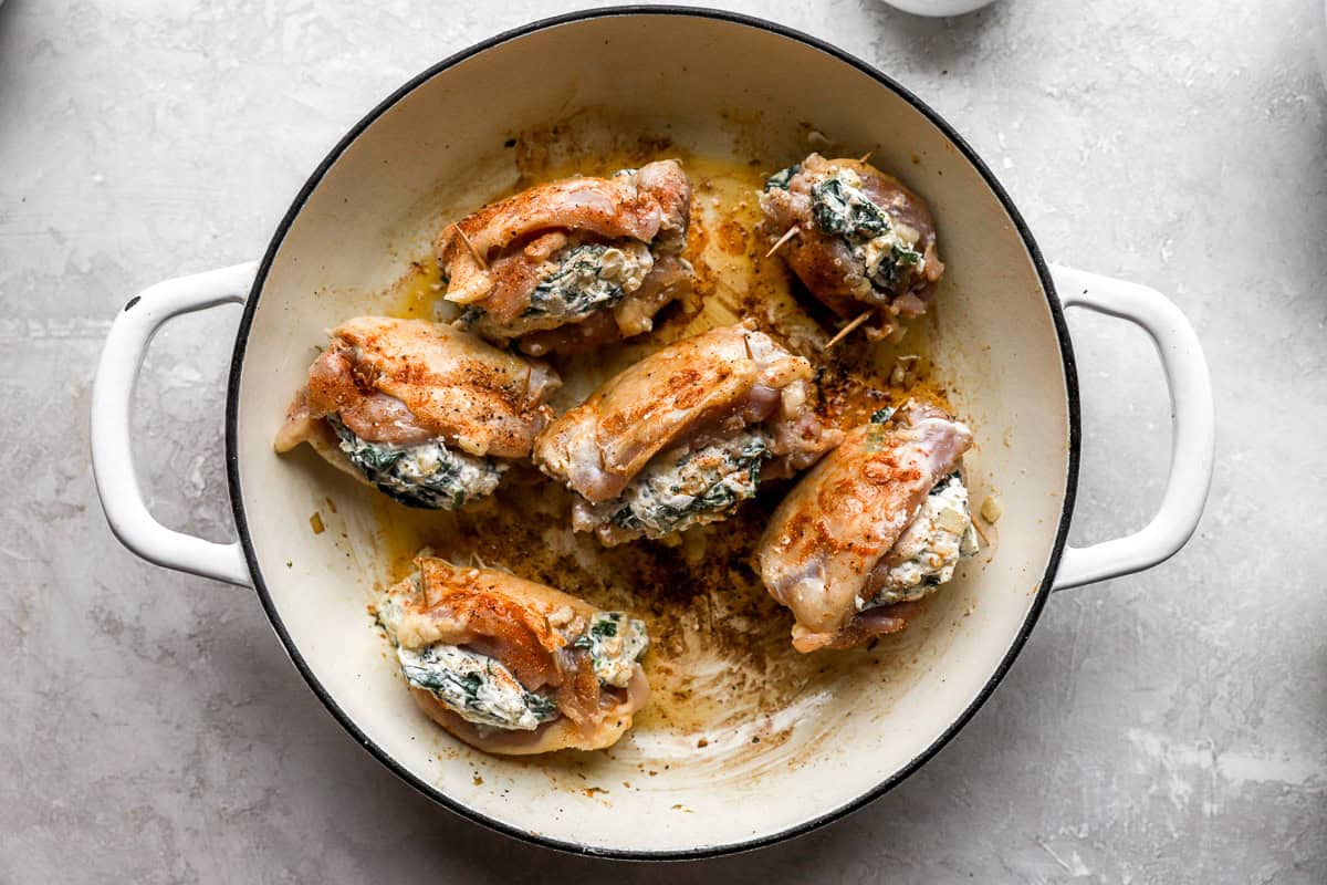 searing stuffed chicken thighs in a pan.