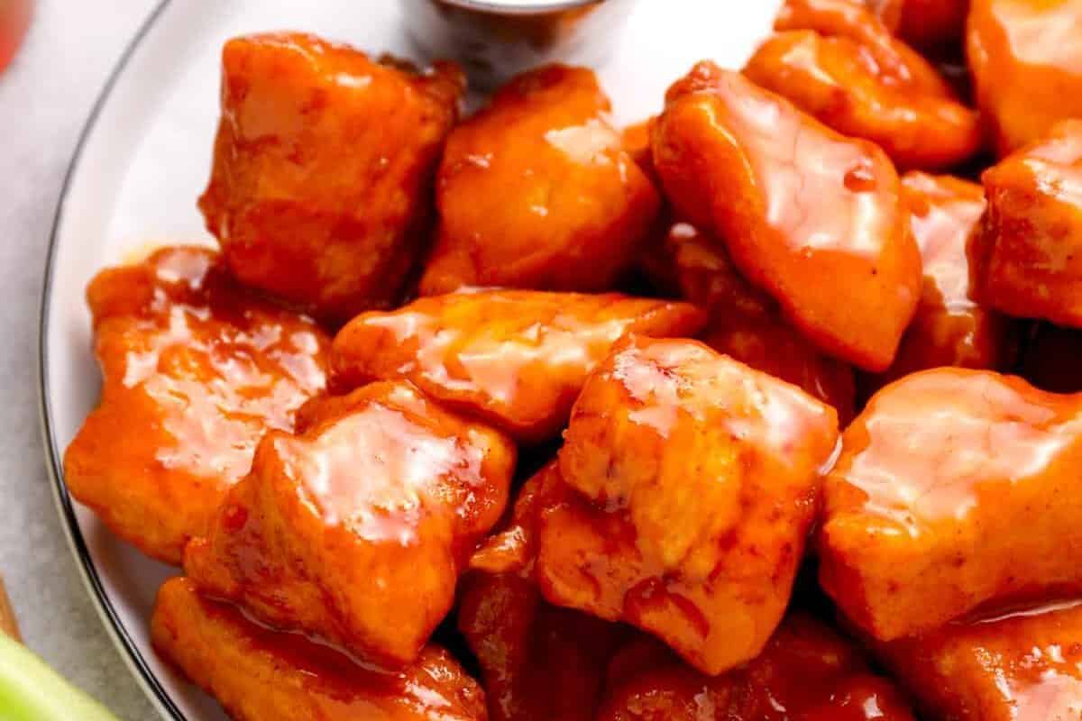 a plate of boneless chicken wings covered in buffalo sauce