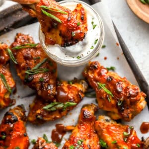 dipping a crockpot chicken wing in ranch.