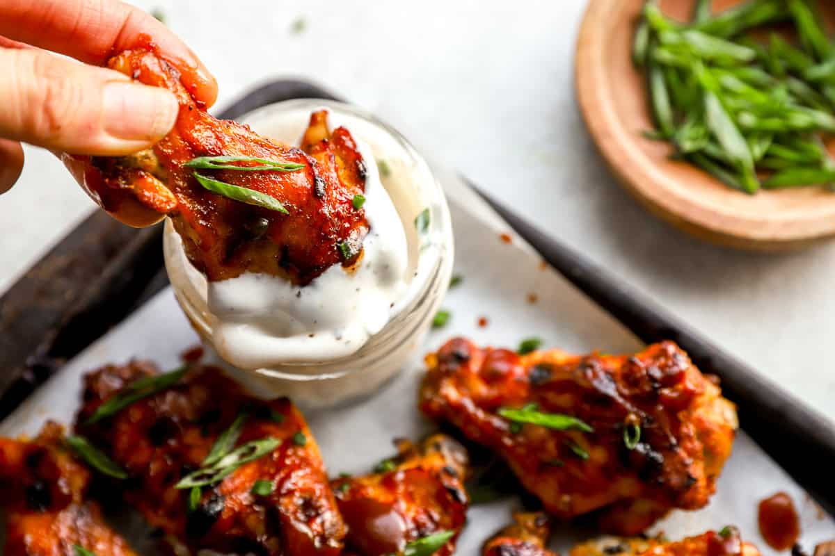 dipping a BBQ buffalo chicken wing in ranch.