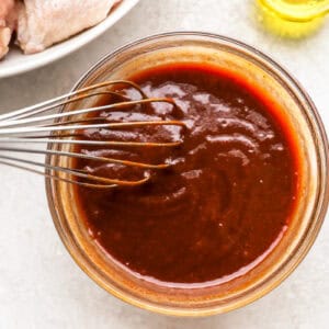 bbq hot wing sauce in a glass bowl with a whisk.