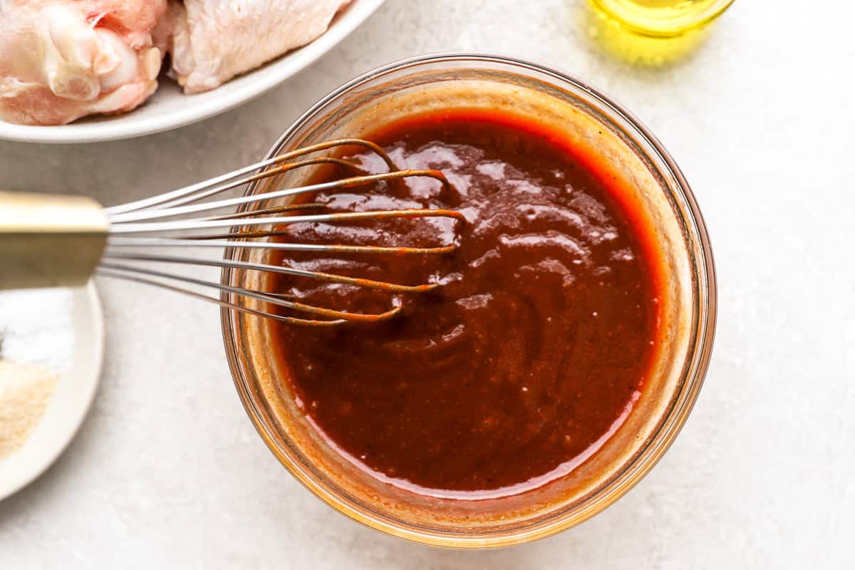 bbq hot wing sauce in a glass bowl with a whisk.