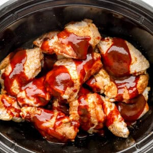 sauce poured over seasoned chicken wings in a crockpot.