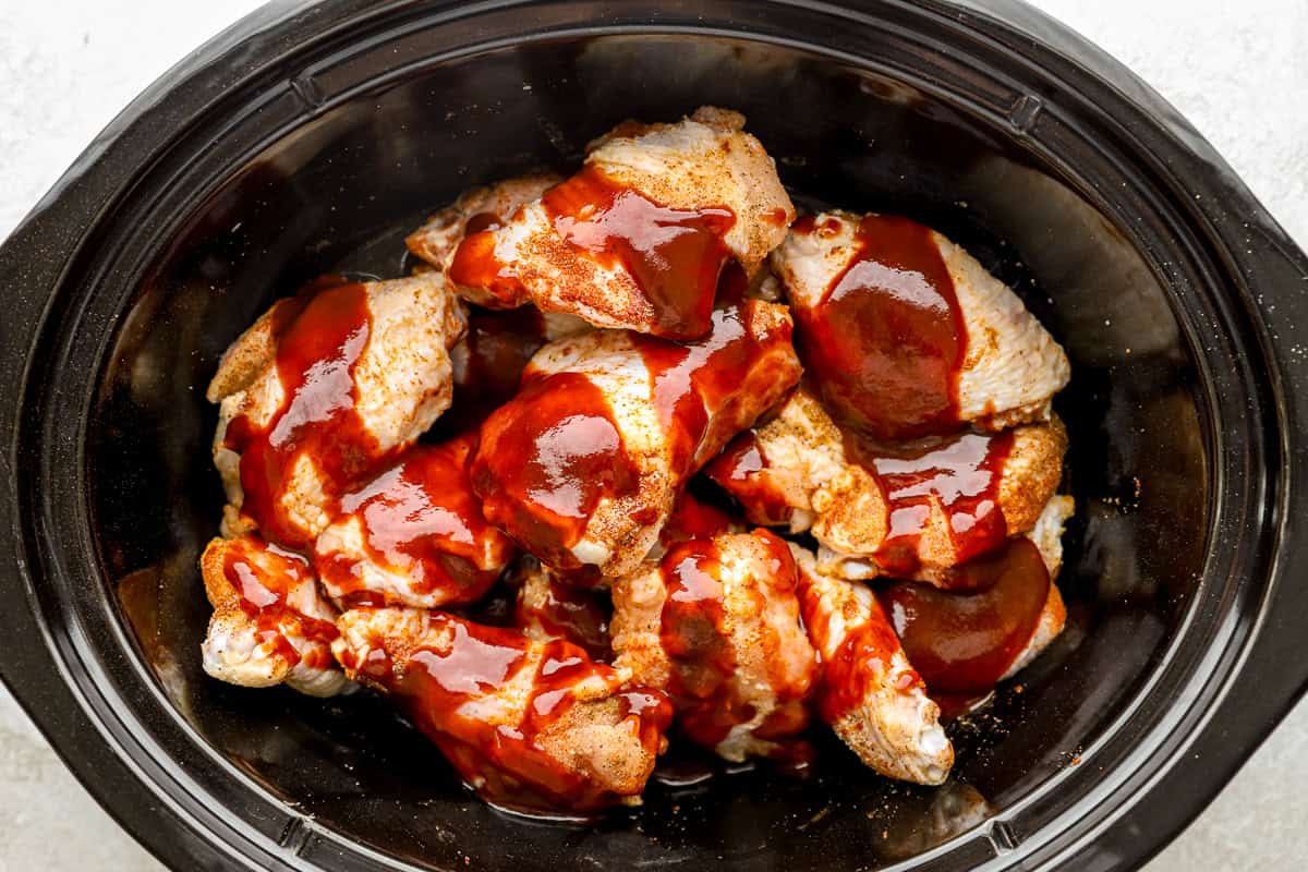 sauce poured over seasoned chicken wings in a slow cooker.