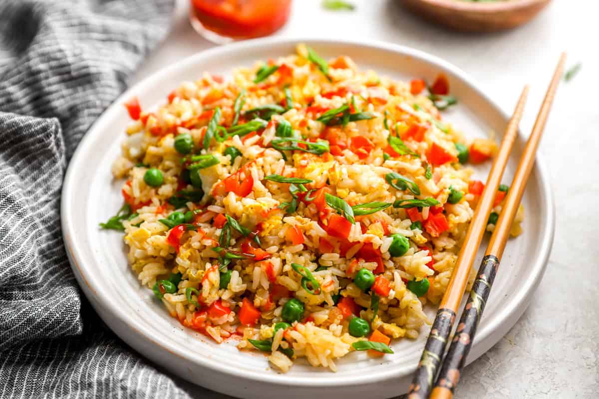 three-quarters view of a serving of fried rice on a white plate with chopsticks.