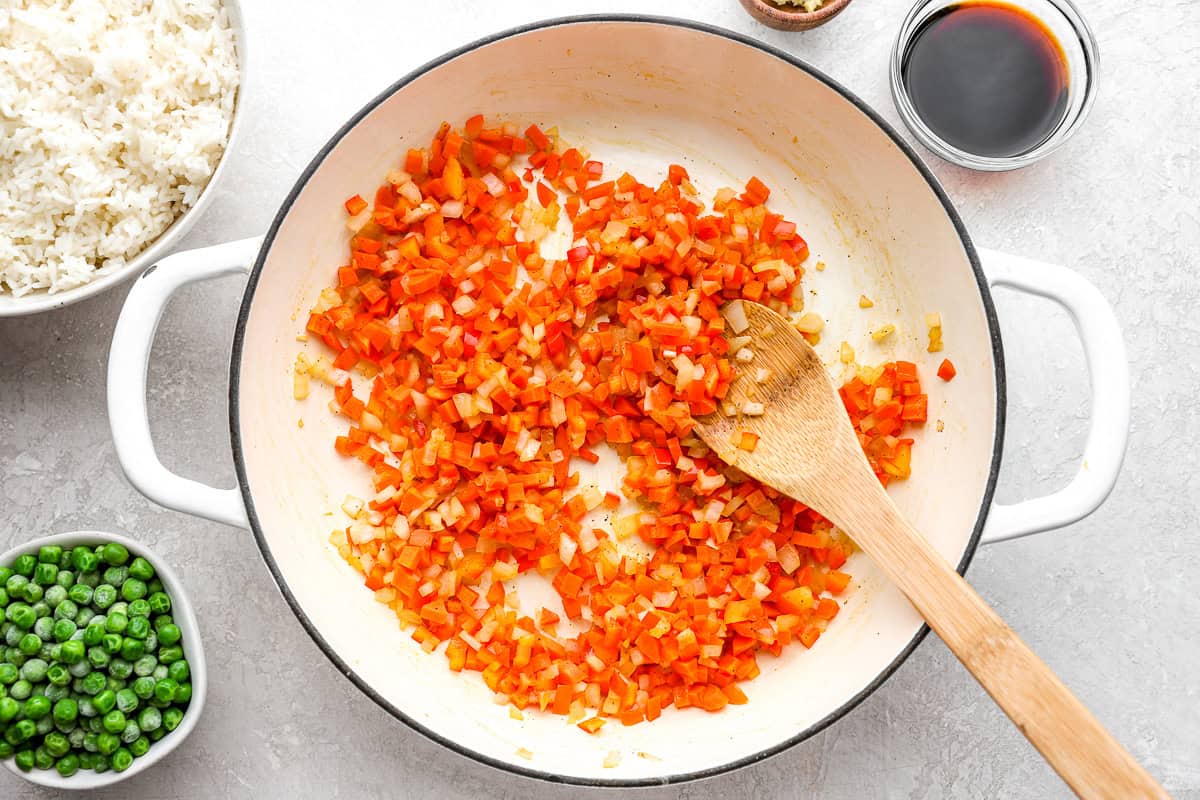 diced veggies in a pan with a wooden spoon.