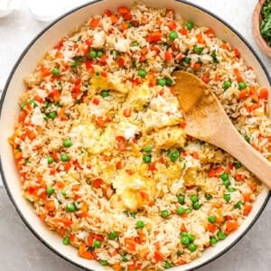 scrambled eggs in the center of a pan with rice and veggies.