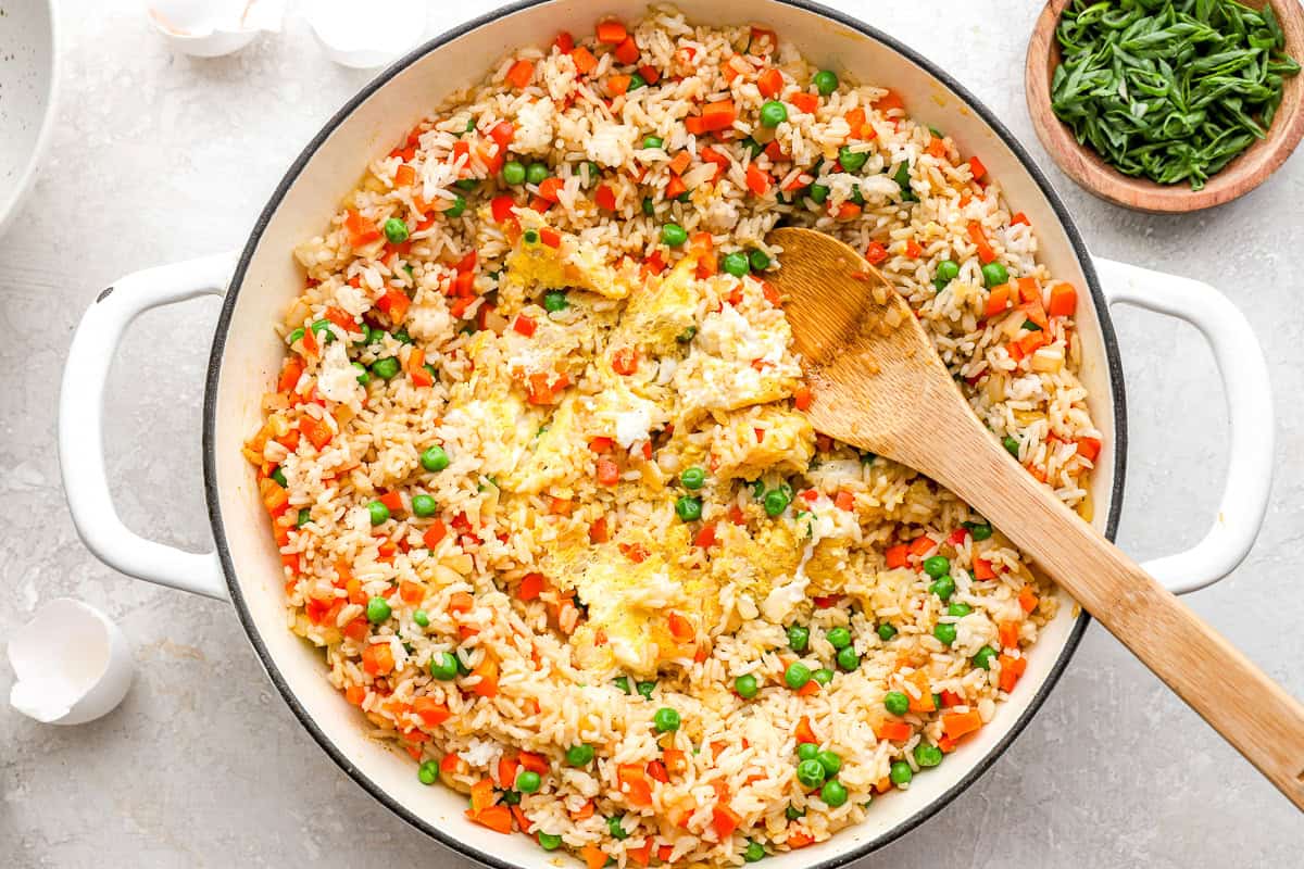 scrambled eggs in the center of a pan with rice and veggies.