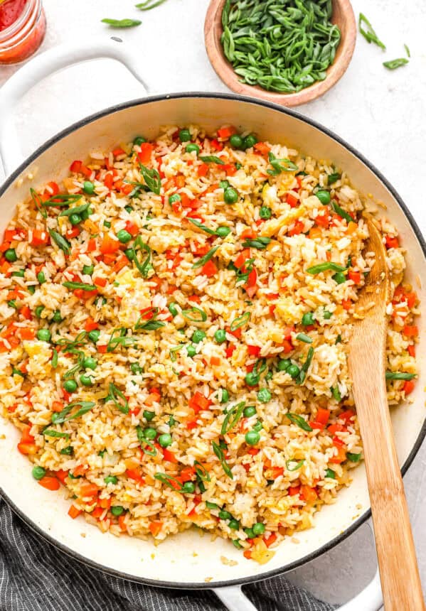 overhead view of fried rice in a pan with a wooden spoon.