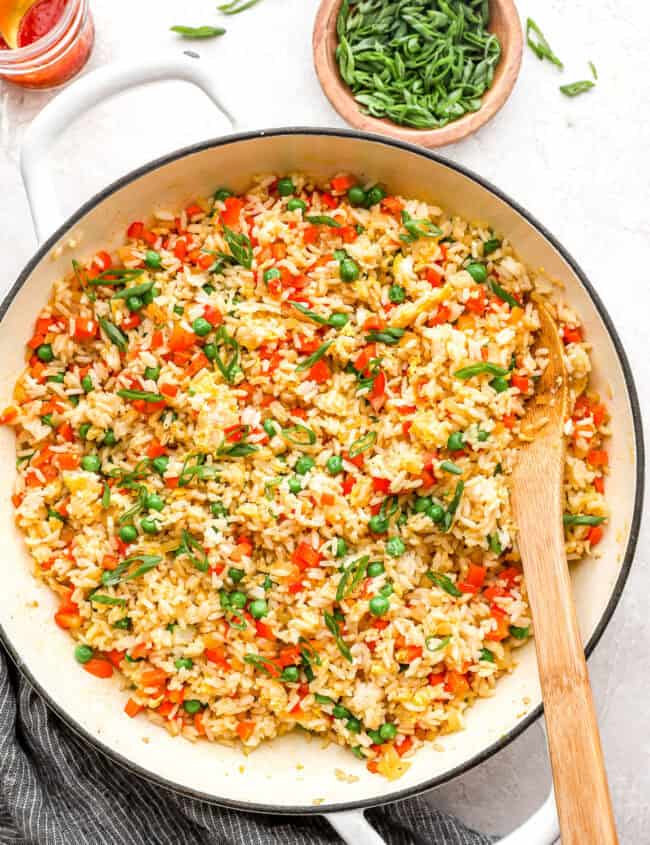 overhead view of fried rice in a pan with a wooden spoon.