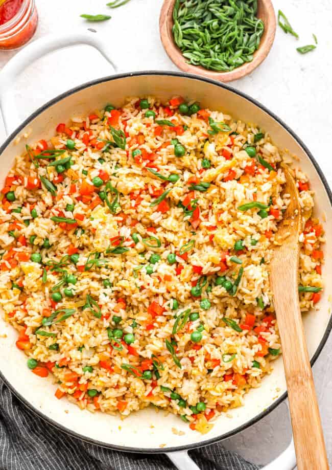 overhead view of fried rice in a pan with a wooden spoon.