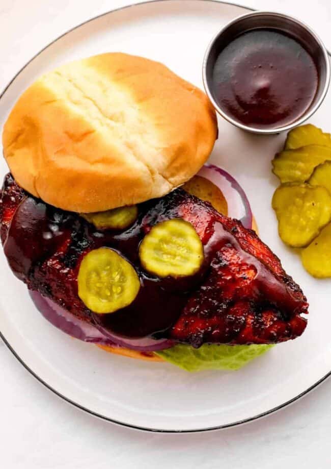 chicken breast sandwich on a plate with pickles.