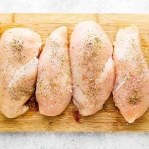 seasoned chicken breasts on a wood cutting board.