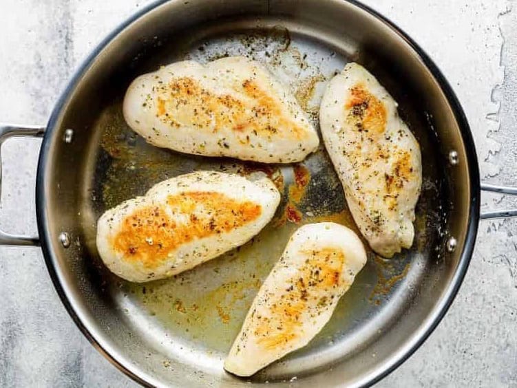 searing chicken breasts in a pan.