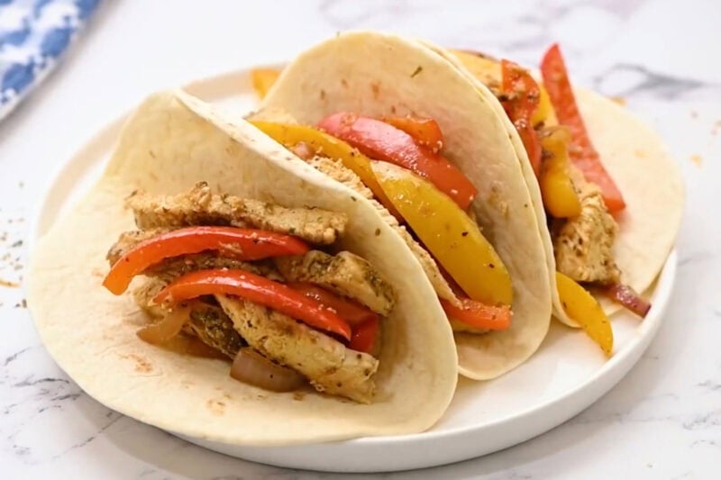 chicken fajita filling in tortillas on a plate.