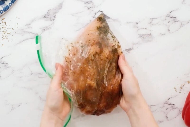 four raw chicken breasts in fajita marinade in a ziplock bag.