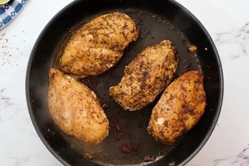 4 cooked fajita seasoned chicken breasts in a skillet.