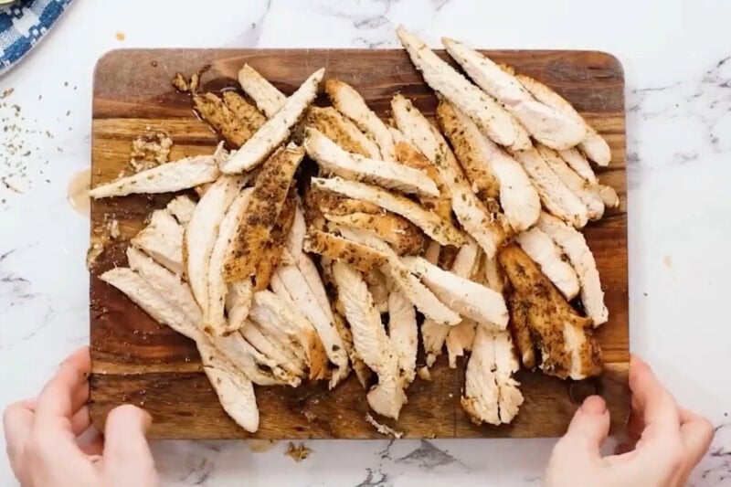 fajita chicken sliced into strips on a cutting board.