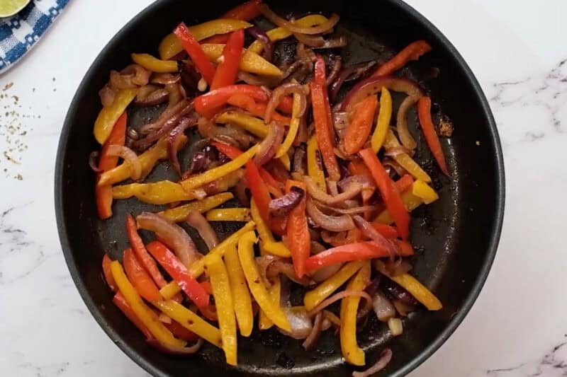 reheating sauteed sliced peppers and onions in a skillet.