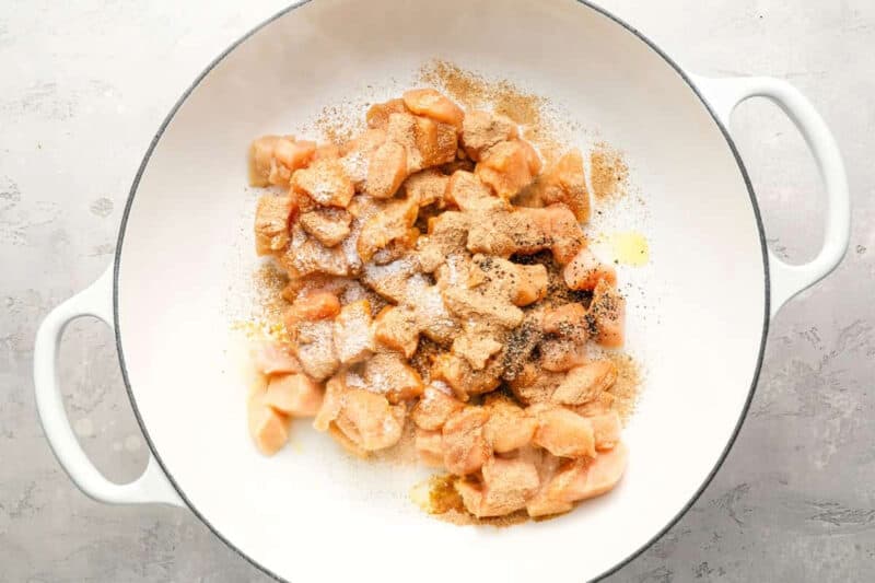 seasoned raw chopped chicken in a pan.