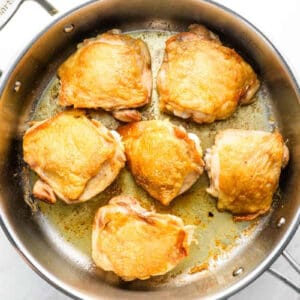 seared chicken thighs in a sauté pan.