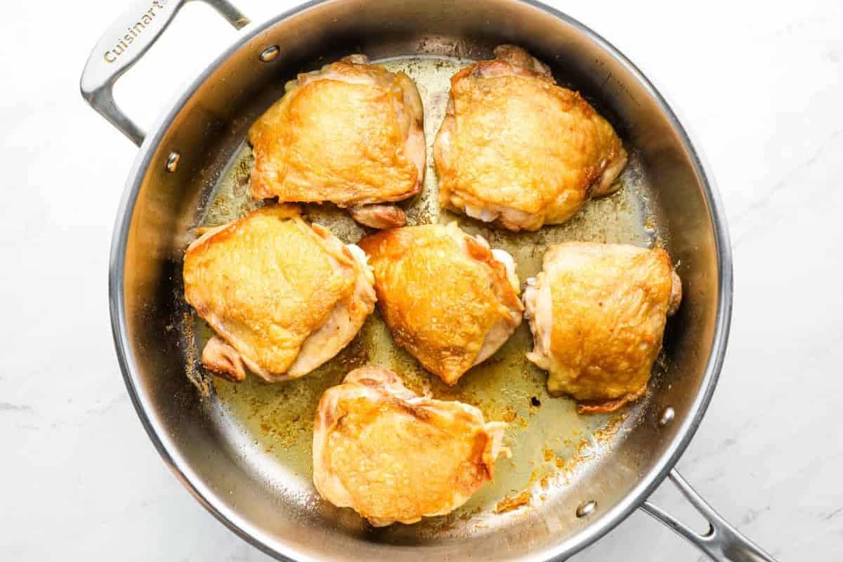 seared chicken thighs in a sauté pan.