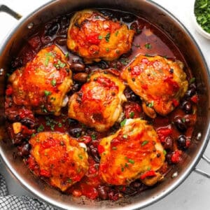 chicken puttanesca in a sauté pan topped with chopped parsley.