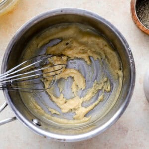 whisking a butter and flour roux in a saucepan.