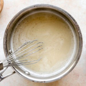 simmering chicken gravy in a saucepan with a whisk.
