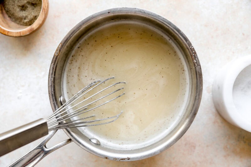 simmering chicken gravy in a saucepan with a whisk.