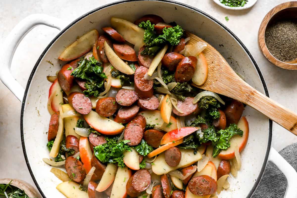 apple chicken sausage skillet with a wooden spoon.
