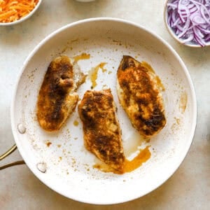 seasoned seared chicken breasts in a pan.