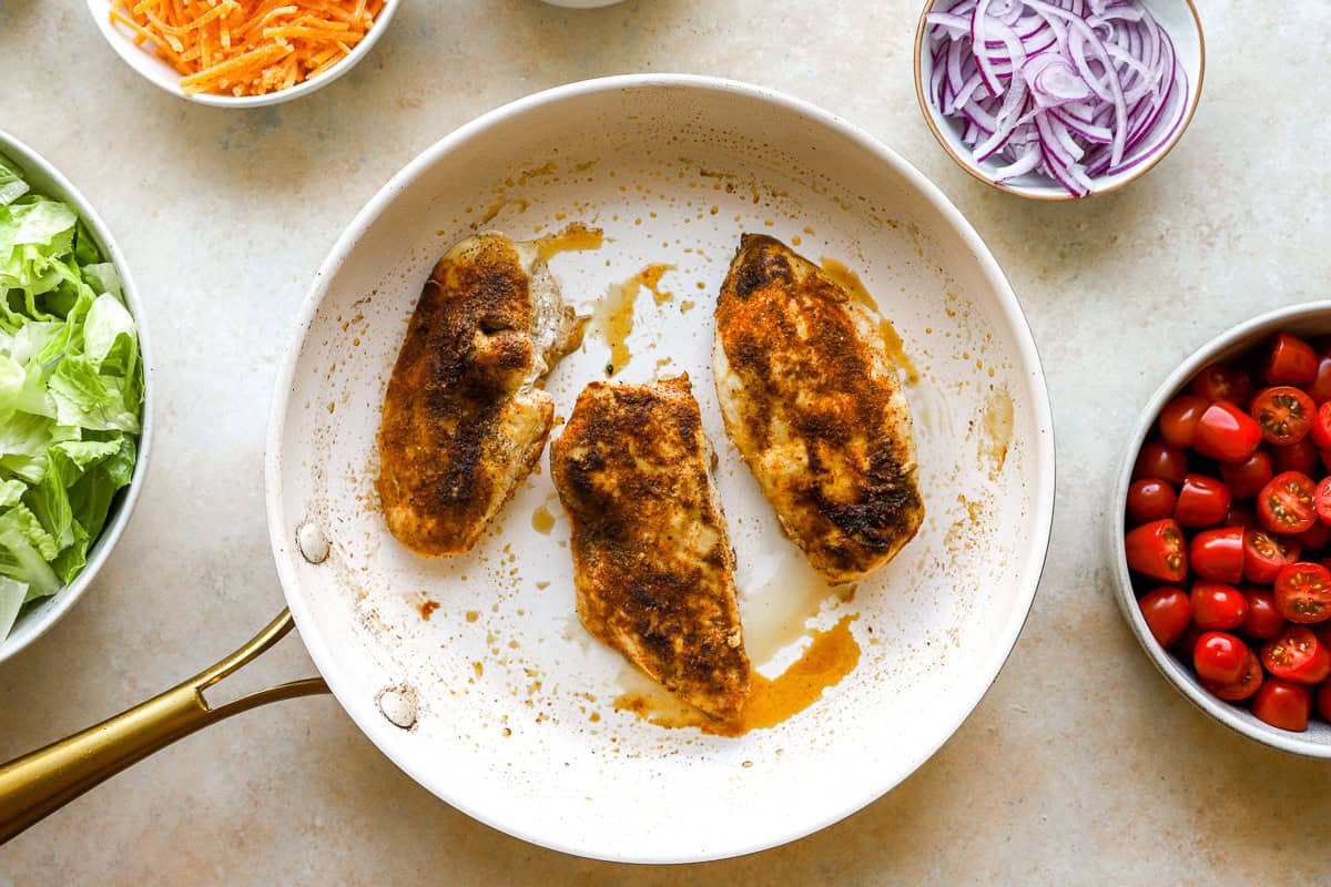 seasoned seared chicken breasts in a pan.