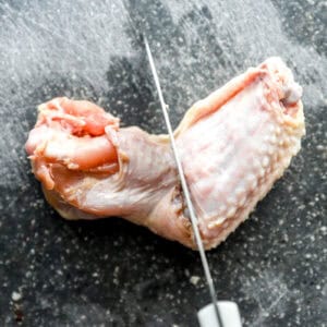 a knife positioned over the joint between a wing flat and drumstick.
